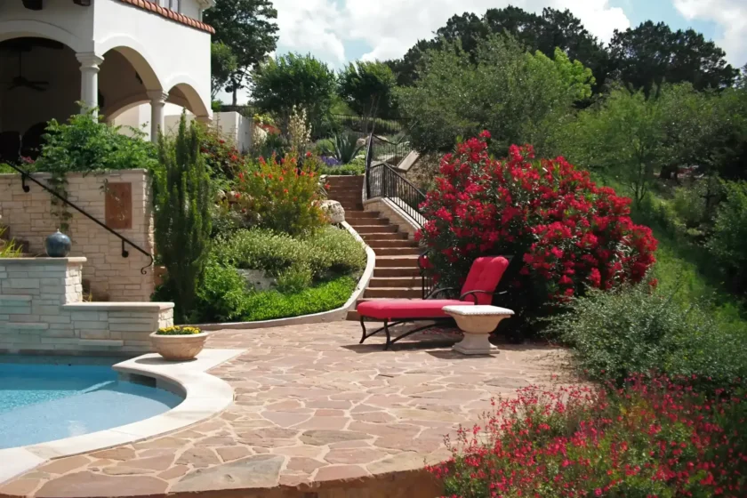 Hillside poolside landscape featuring tiered stone retaining walls, greenery, a flagstone patio, and a scenic valley view.